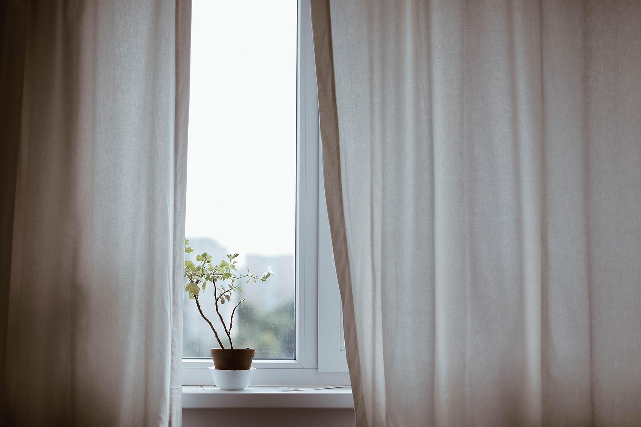 Transparante gordijnen met zonnestralen in woonkamer.